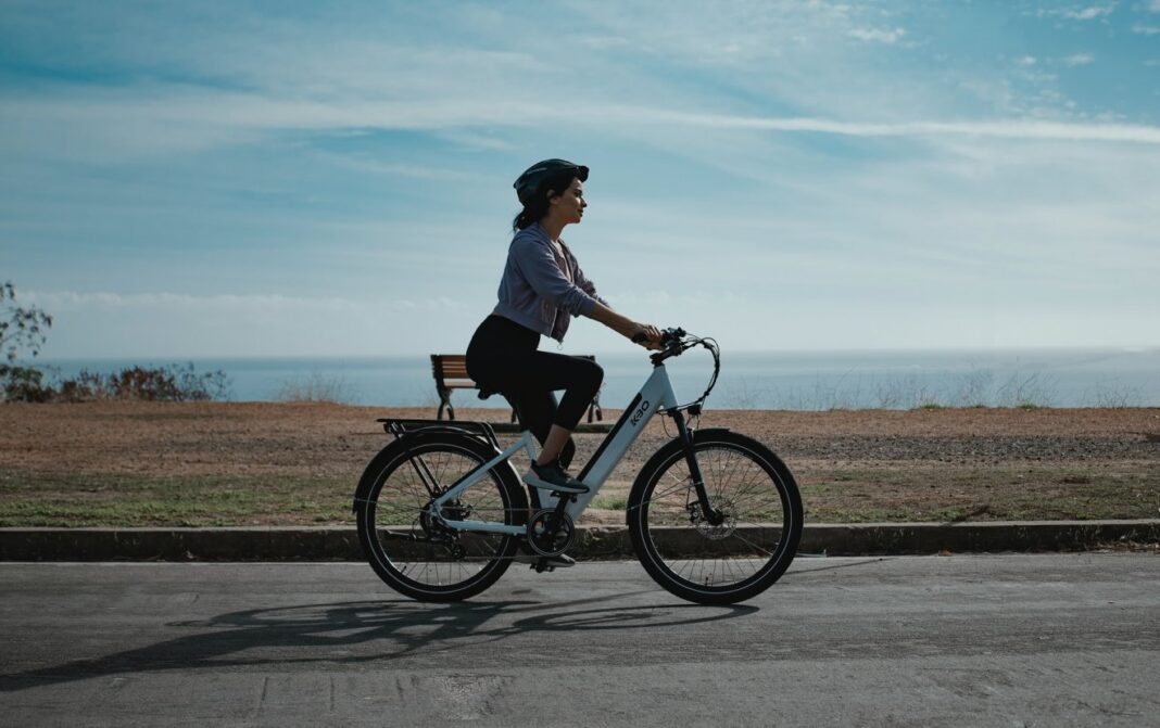 kobieta jedzie na elektrycznym rowerze brzegiem morza